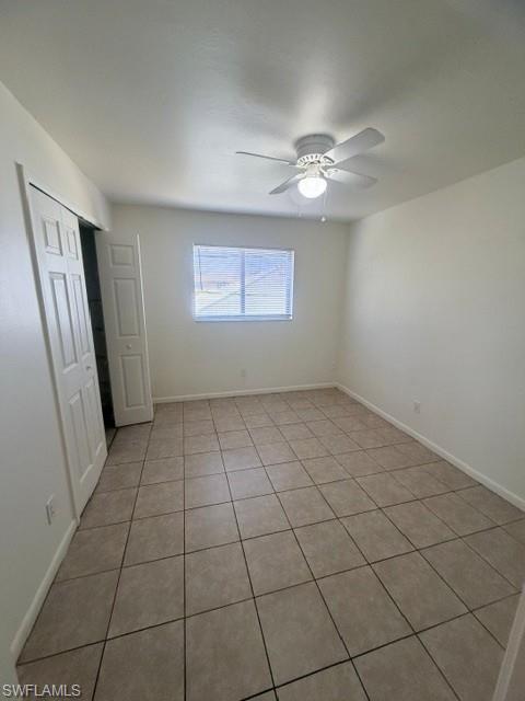 Spacious room featuring neutral tile flooring, light-colored walls, and a window with blinds