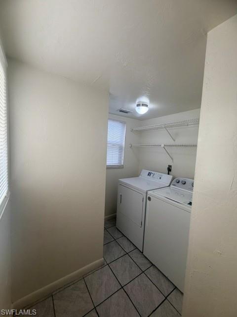 Dedicated laundry area featuring tile flooring, built-in wire shelving, and a window for natural light
