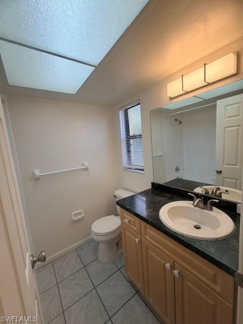 Bathroom featuring a light wood-finish vanity with a dark countertop and an integrated sink, a large mirror, a privacy window, and tiled flooring