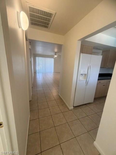 Tiled entryway opening to a living area with wood-finish flooring and a ceiling fan