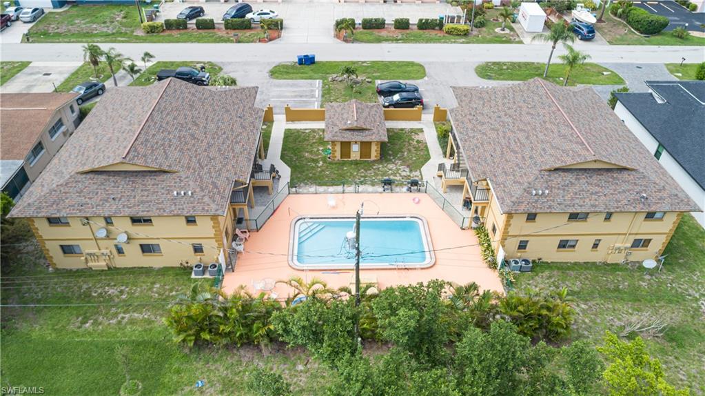 Multi-unit property featuring two two-story buildings, a central swimming pool, and a fenced pool deck
