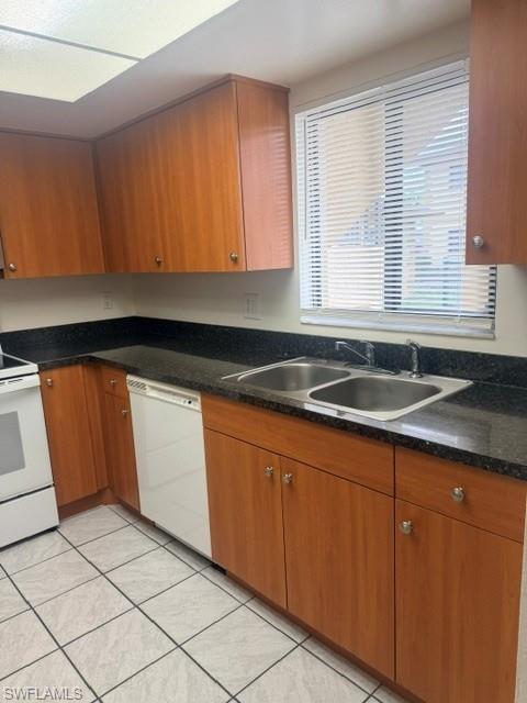 Kitchen featuring wood-finish cabinetry, dark speckled countertops, and a double basin stainless steel sink
