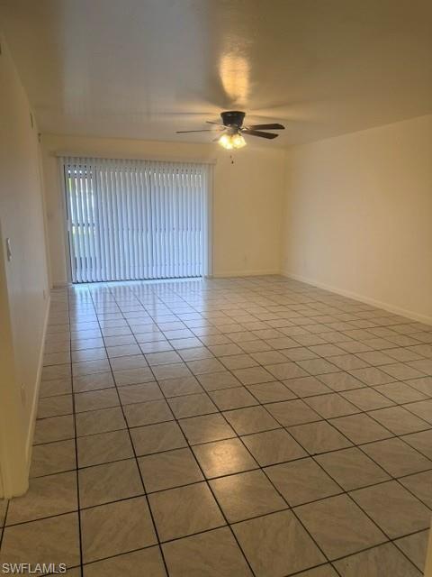 Spacious room featuring light-toned tile flooring, neutral wall paint, and a ceiling fan with integrated lighting
