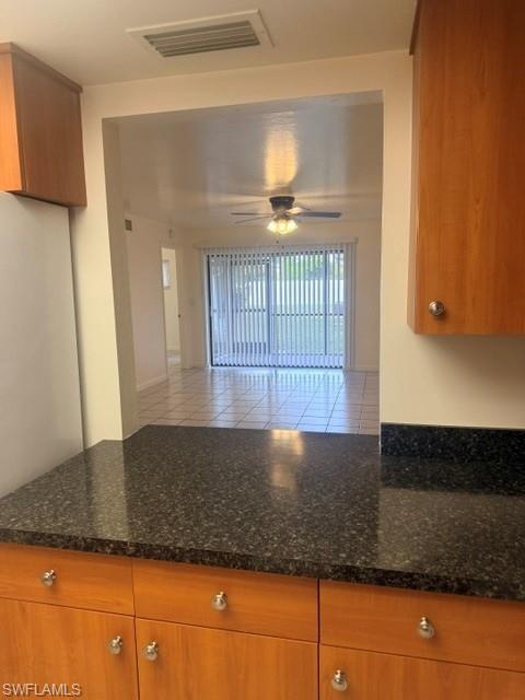 Kitchen countertop featuring a dark speckled surface, wood-finish cabinetry, and silver hardware