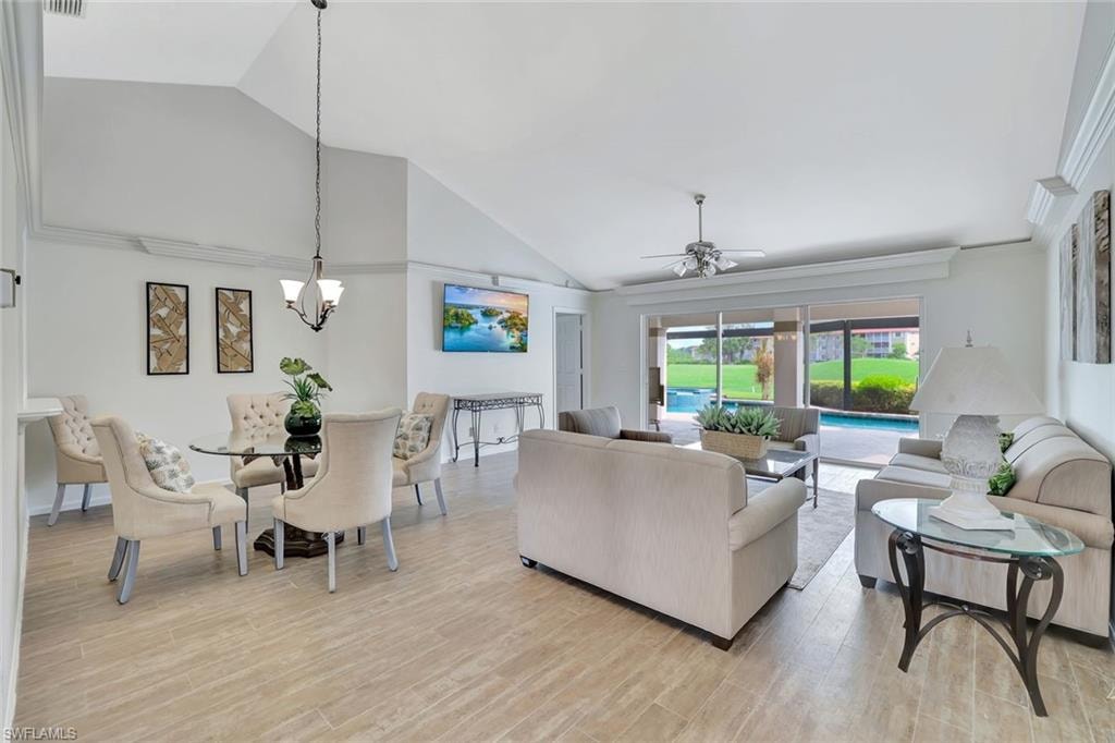 Living room with vaulted ceiling, ceiling fan, a chandelier, and light wood finished floors