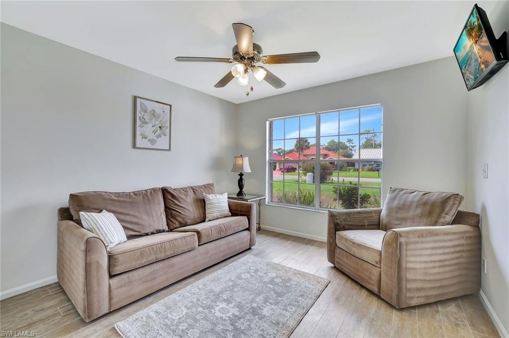 Living room featuring baseboards, light wood-style floors, and a ceiling fan