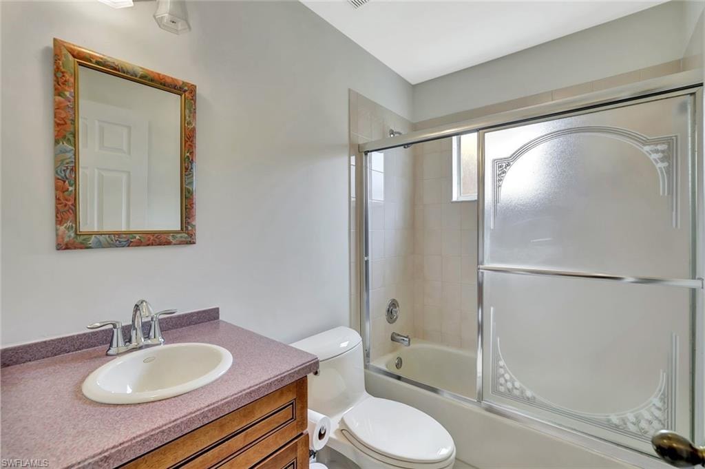 Bathroom featuring toilet, vanity, and enclosed tub / shower combo