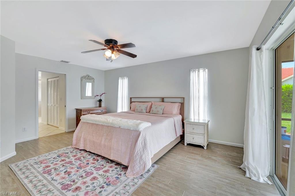 Bedroom with multiple windows, baseboards, and light wood-style floors