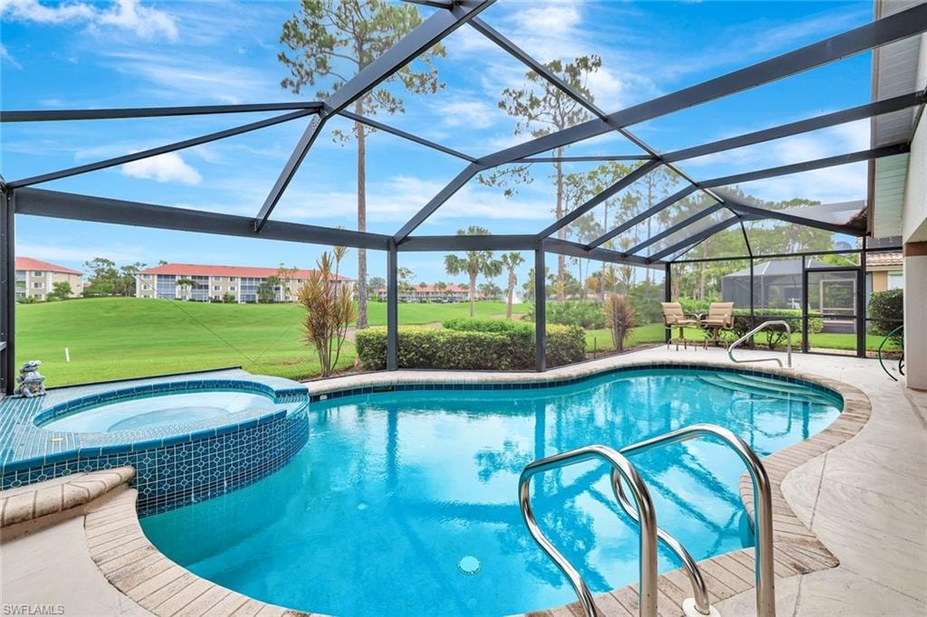 View of swimming pool featuring a lawn, a patio area, a pool with connected hot tub, and glass enclosure