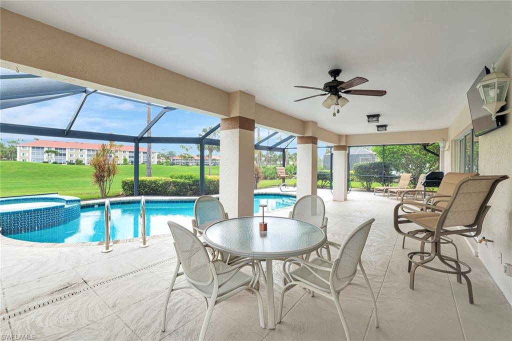 View of pool featuring ceiling fan, a patio area, a pool with connected hot tub, a lanai, and a yard
