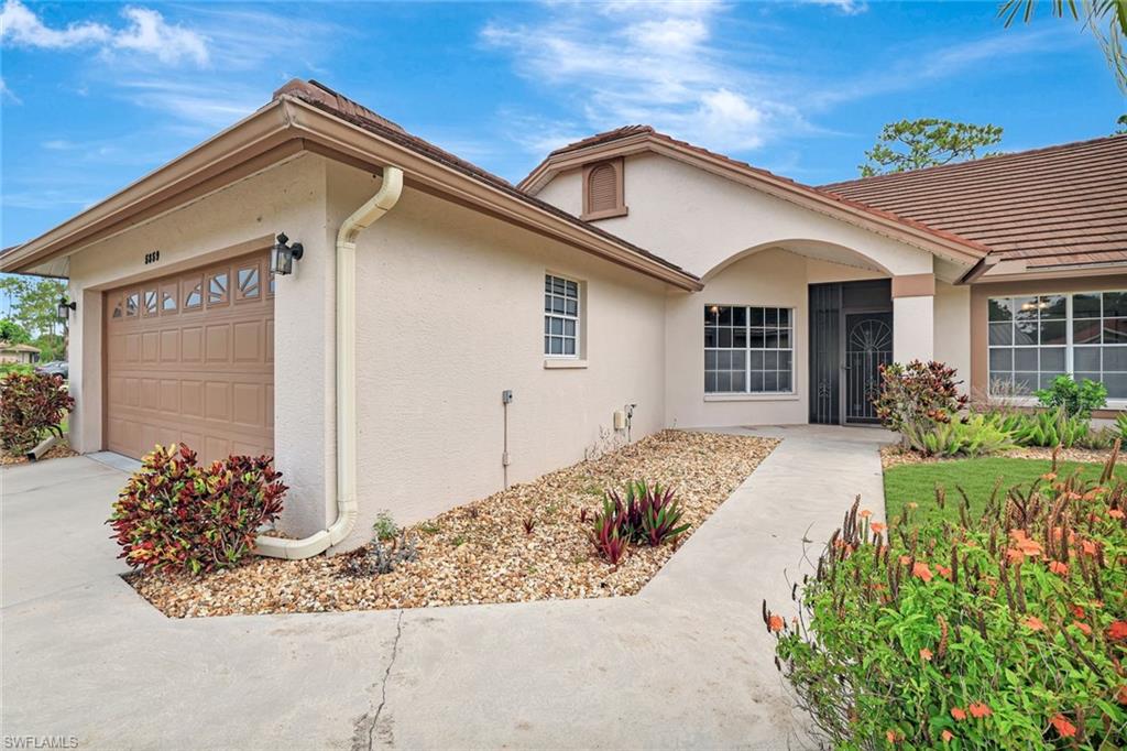 View of front facade featuring stucco siding, a garage, a tile roof, and concrete driveway
