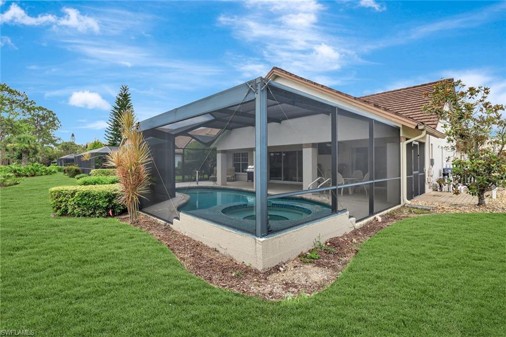 Rear view of property with an in-ground hot tub, a patio, a yard, an outdoor pool, and a tiled roof