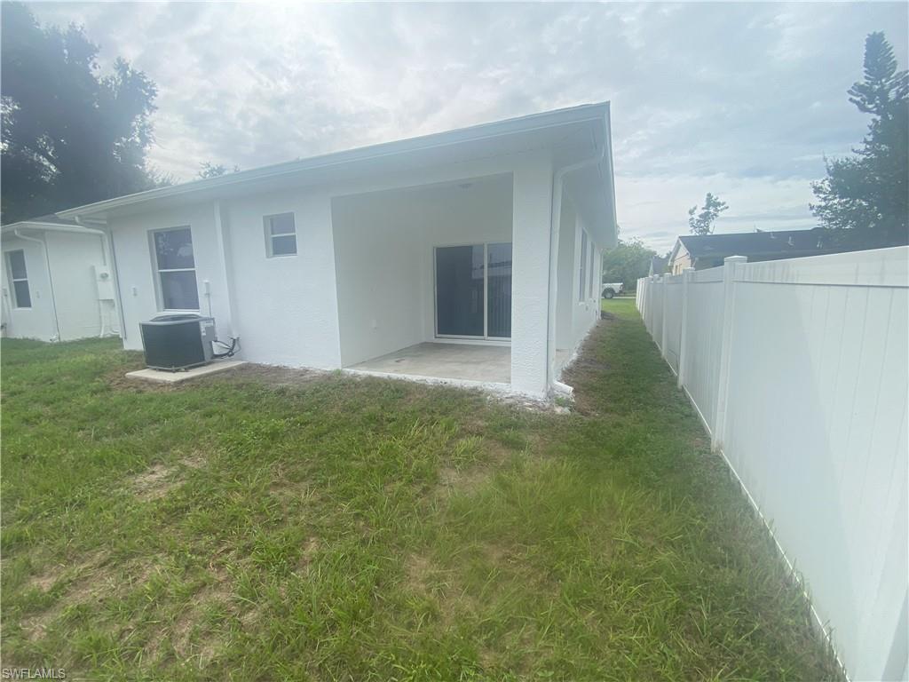 Rear exterior featuring a covered patio, sliding glass door, and white privacy fencing