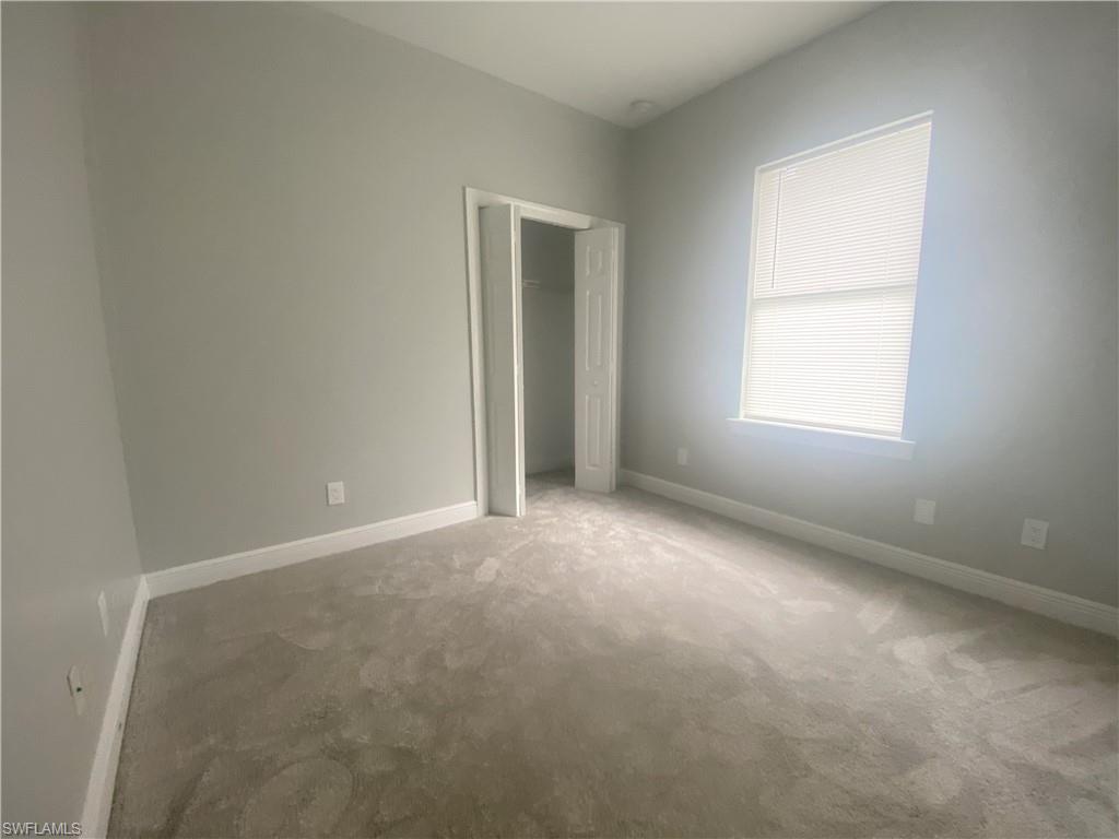 Carpeted room featuring a single window with blinds, light gray wall paint, and white trim