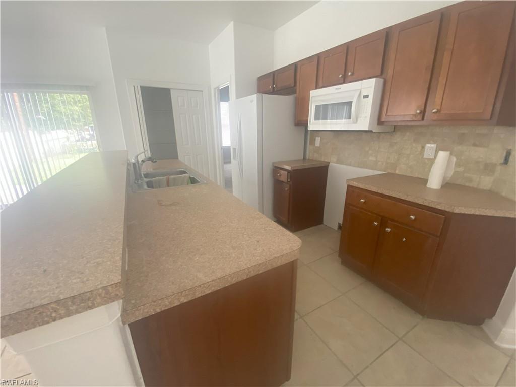 Kitchen featuring wood-finish cabinetry, speckled countertops, and a white over-the-range microwave