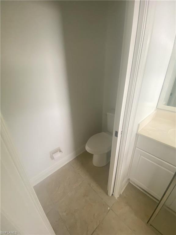 Water closet featuring a white commode and neutral-toned floor tiling