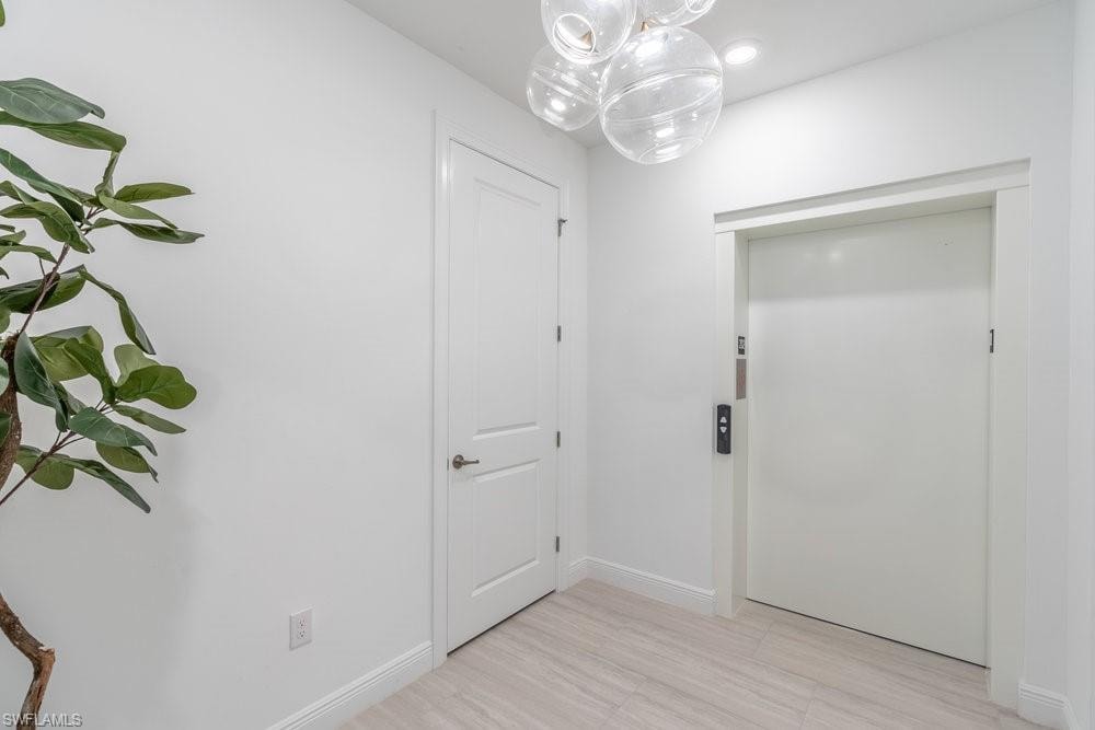 Doorway to outside featuring an inviting chandelier, elevator, and light tile floors