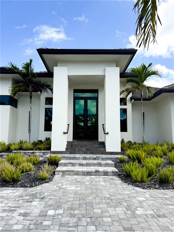 Contemporary exterior with a prominent entry, dual dark-framed glass doors, and a paver walkway