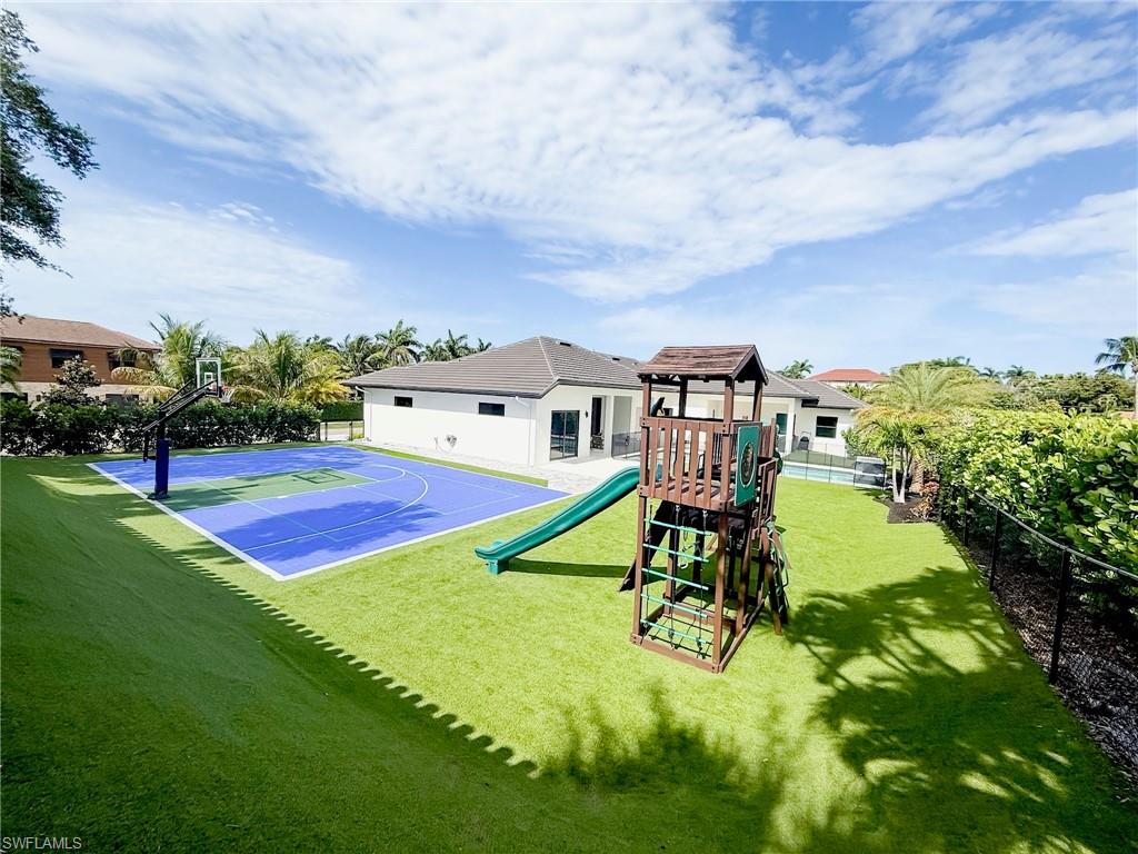 Outdoor multi-sport court with vibrant blue surfacing and kids playground