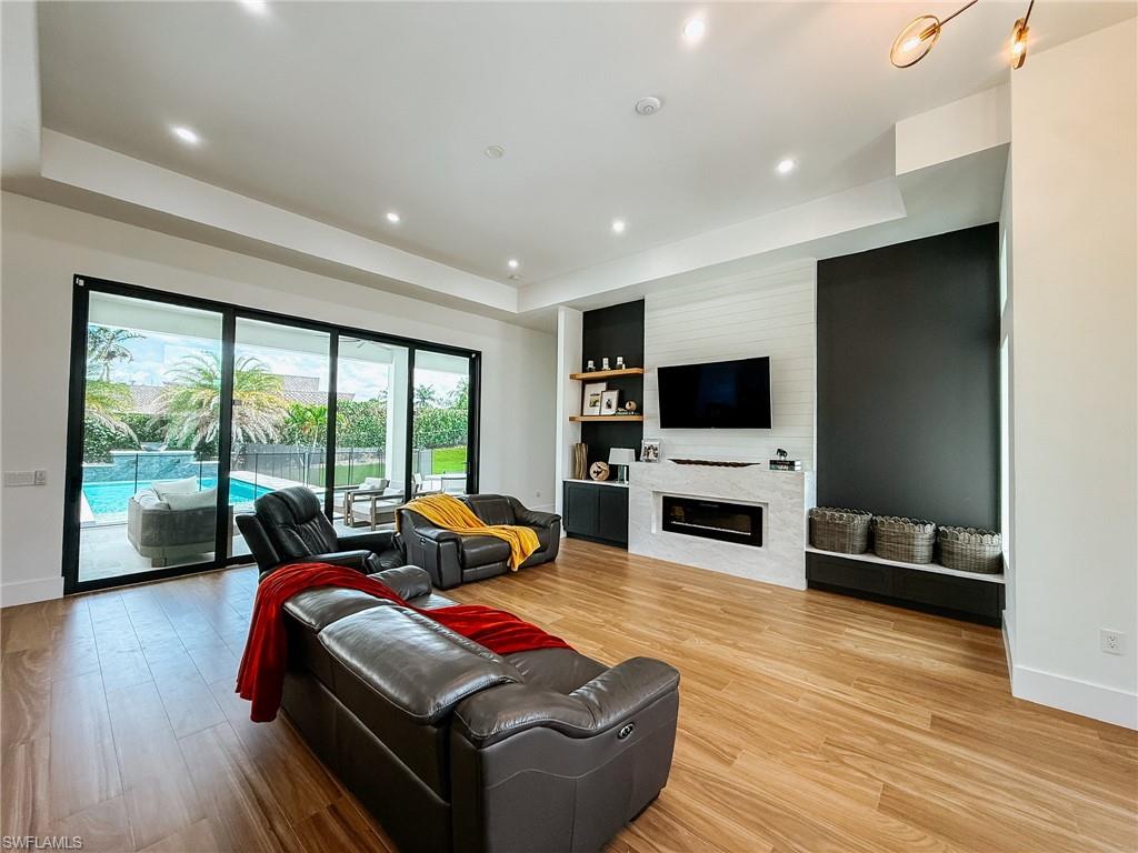 Spacious living area featuring wood-finish flooring, recessed lighting, and a modern built-in entertainment center with a fireplace