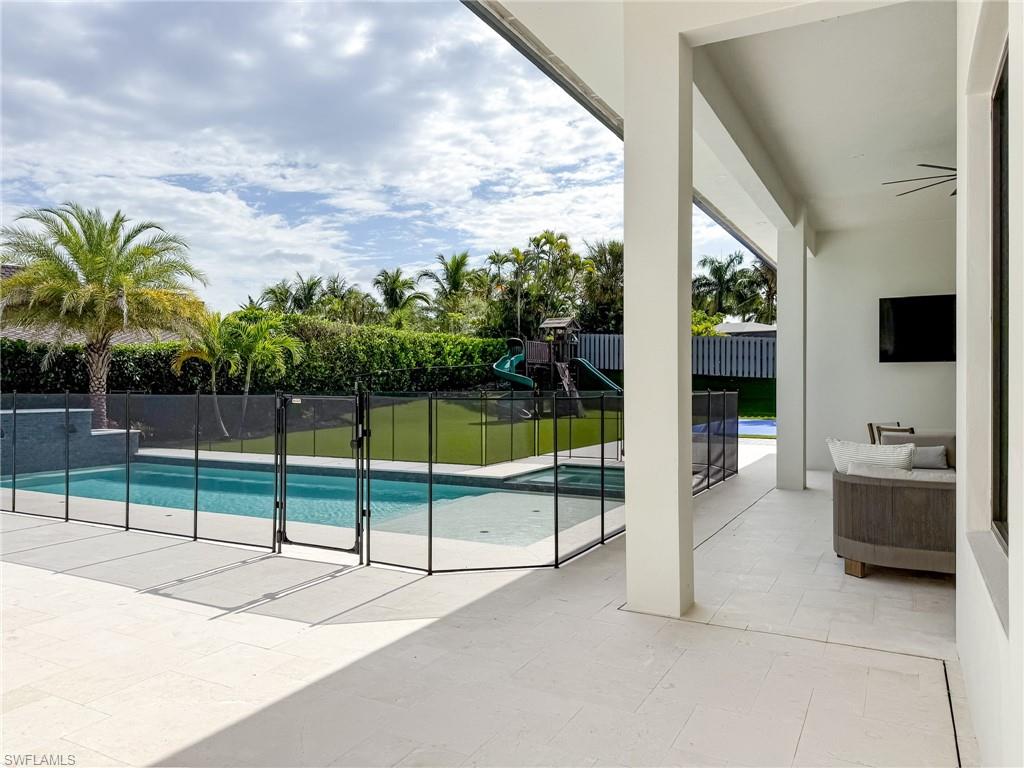 Spacious outdoor living area with a covered patio featuring light-toned tile flooring and recessed lighting