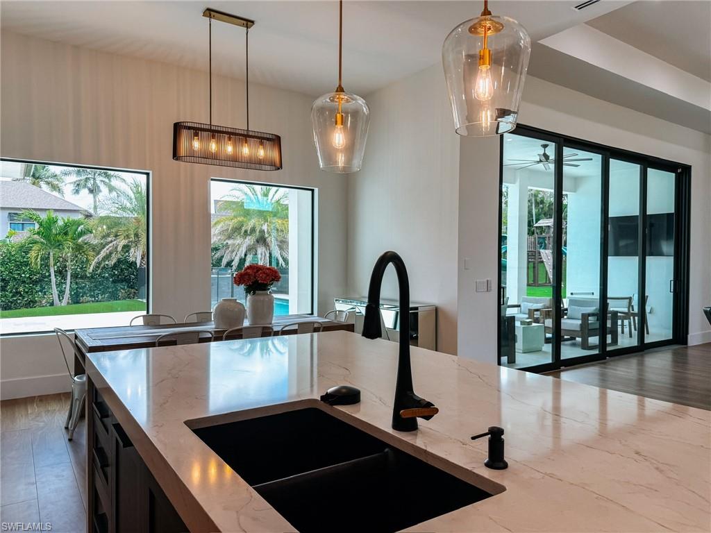 Kitchen island with a matte black faucet and integrated sink, complemented by clear glass pendant lighting