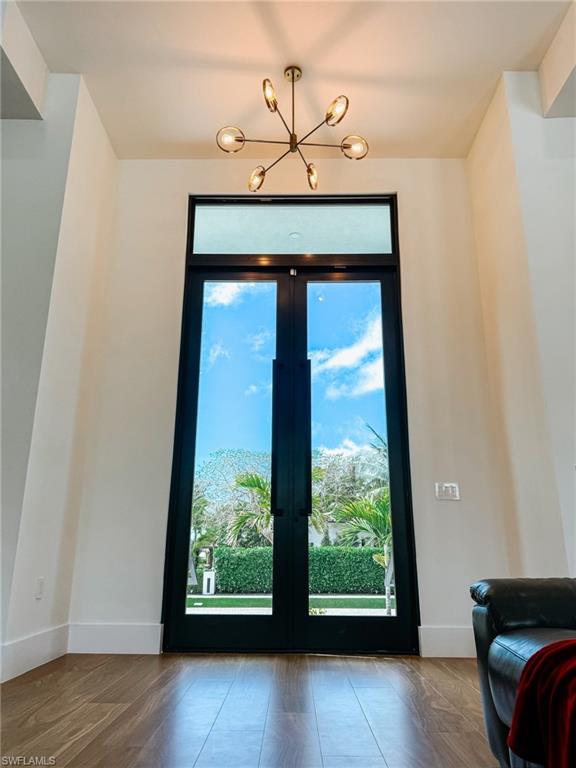 Double-height entry featuring French doors, wood-finish flooring, and lighting fixture