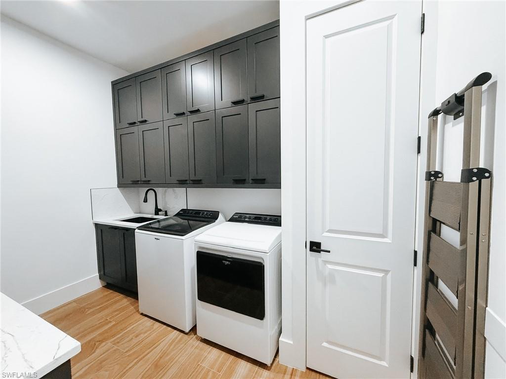 Laundry area featuring extensive dark cabinetry, light countertops, and wood-finish flooring