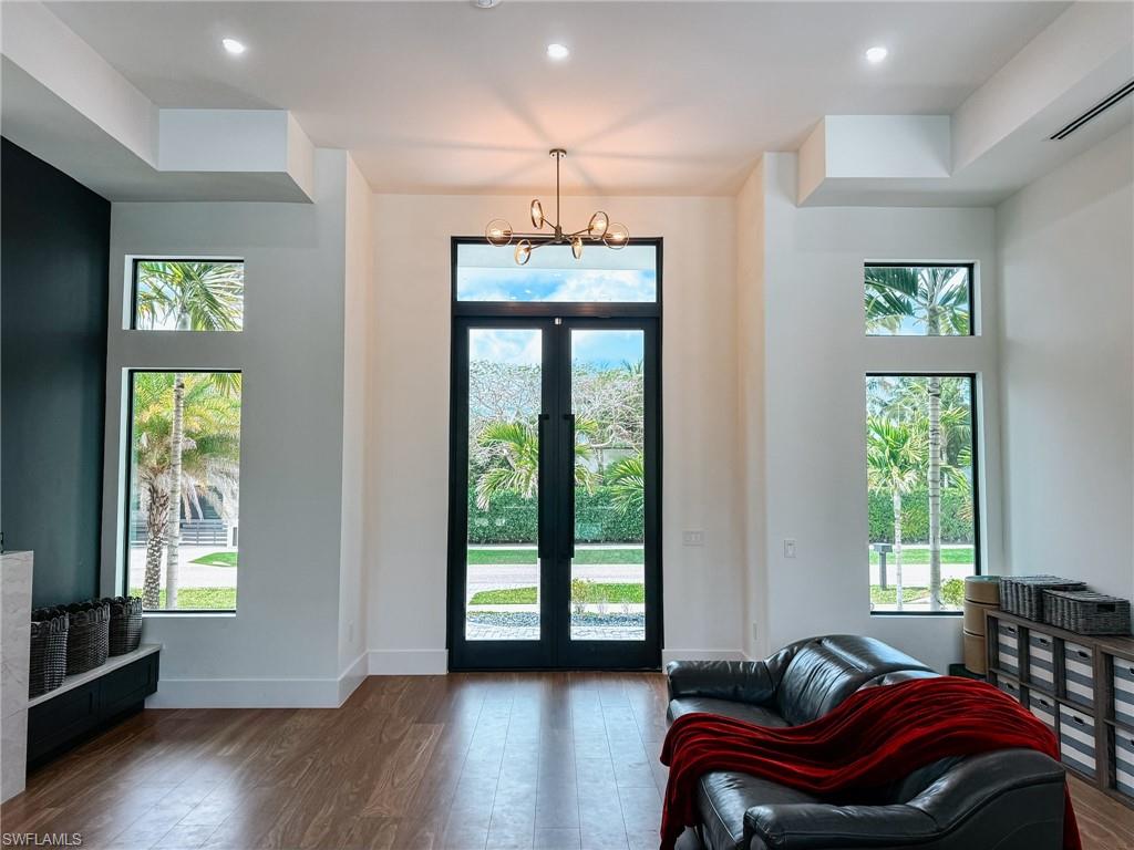 Double-height entry featuring French doors, wood-finish flooring, and recessed lighting