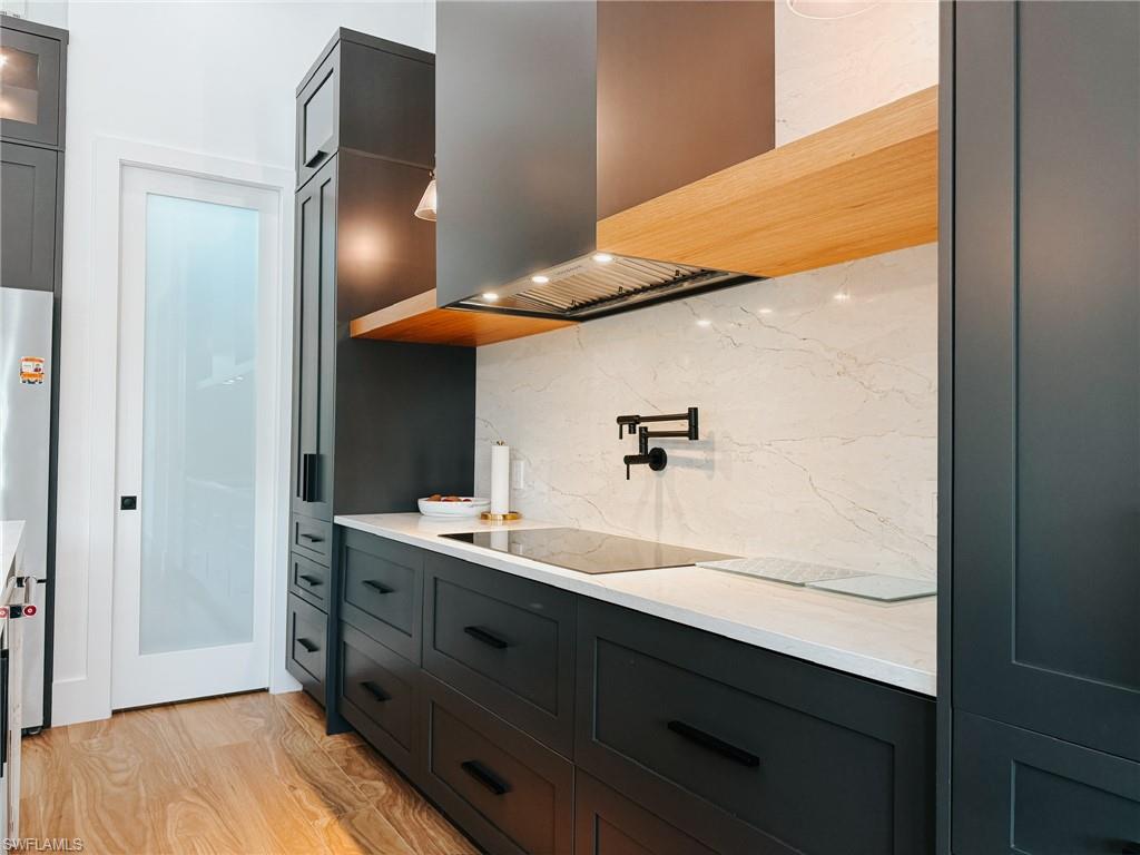 Modern kitchen featuring dark cabinetry, light countertops, and a white marble-patterned backsplash