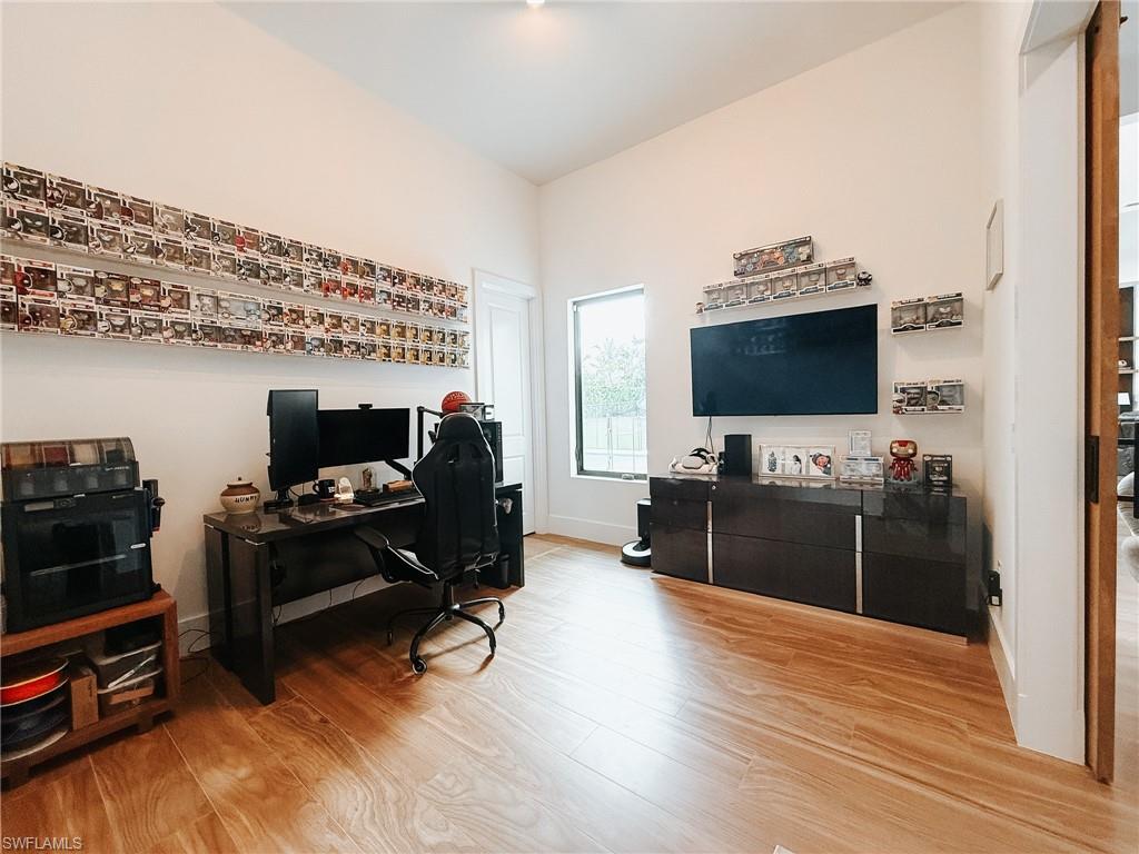 Spacious room featuring vaulted ceilings, wood-finish flooring, a large window, and a wide entryway