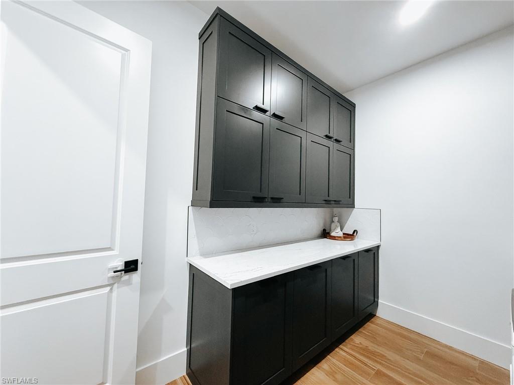 Laundry area featuring extensive dark cabinetry, light countertops, and wood-finish flooring