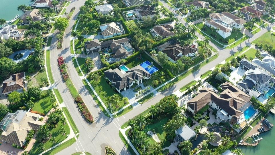 Aerial perspective of a developed residential area featuring multiple single-family homes with private swimming pools and mature landscaping
