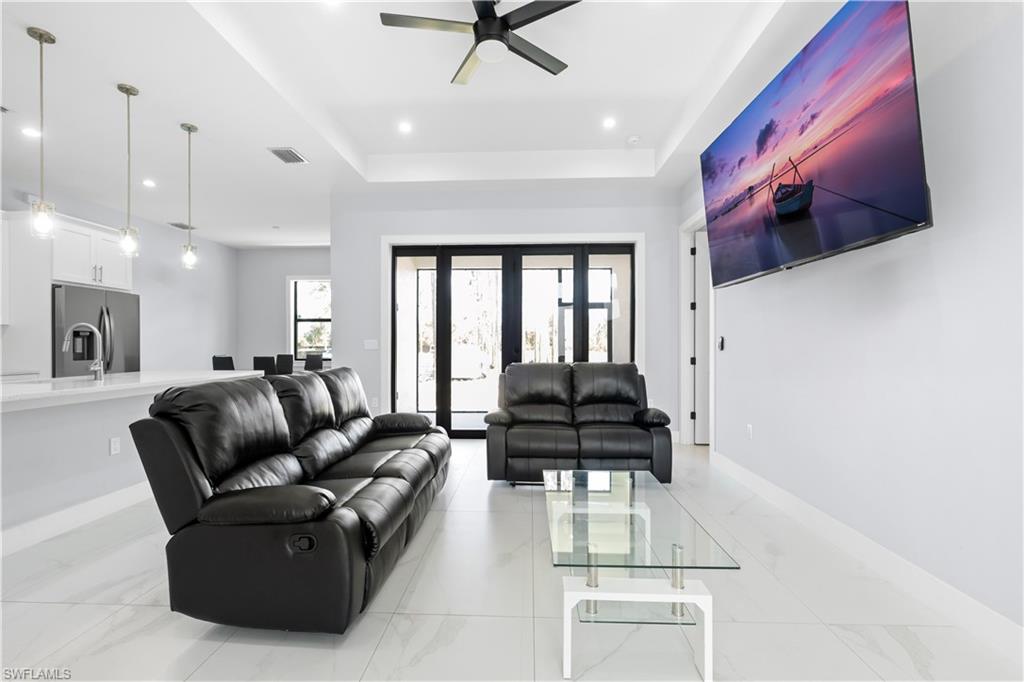 Bright living area featuring white tile flooring, recessed lighting, and a ceiling fan
