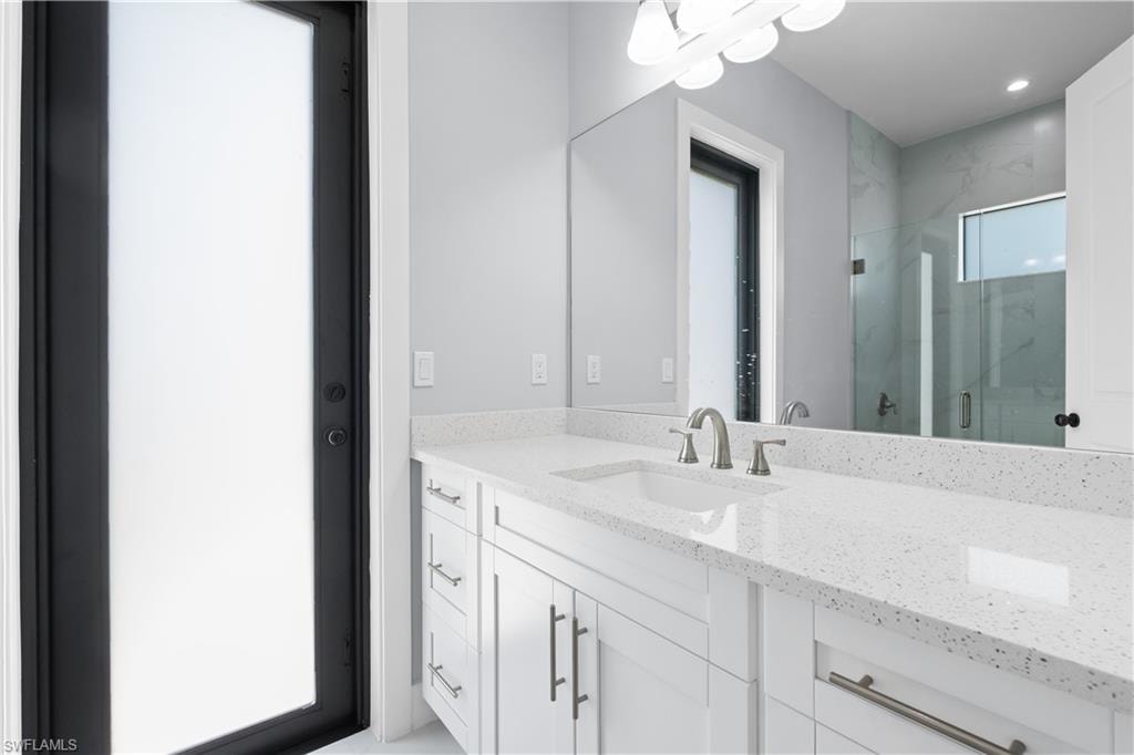 Contemporary bathroom vanity featuring white cabinetry, a light speckled countertop, and an integrated white sink