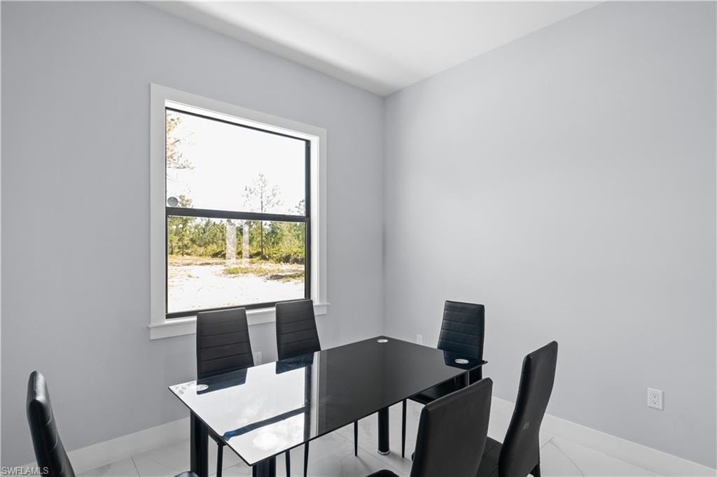 Bright interior space featuring a prominent window, white baseboards, and light-colored walls