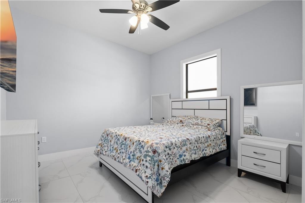 Spacious interior featuring light gray walls, large format tile flooring, and a ceiling fan with integrated lighting