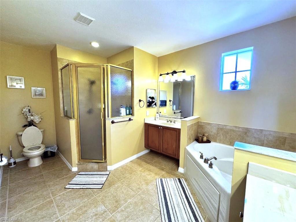 Full bathroom featuring vanity, tile patterned floors, toilet, and separate shower and tub