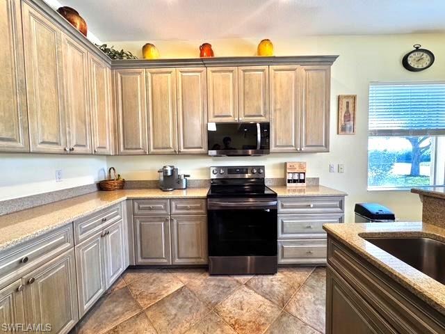 Kitchen with light stone countertops, stainless steel appliances, and sink