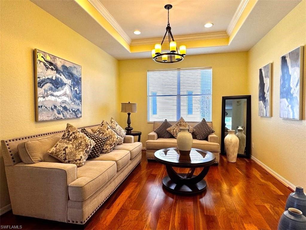Living room with crown molding, dark wood-type flooring, and a tray ceiling