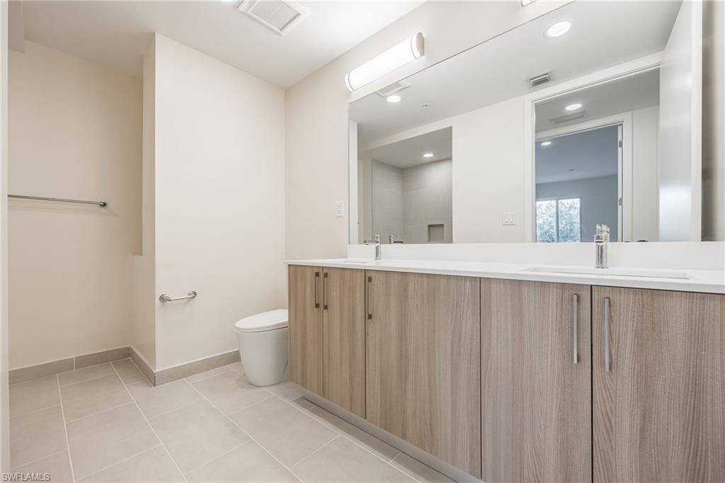 Full bath featuring double vanity, visible vents, toilet, and a sink