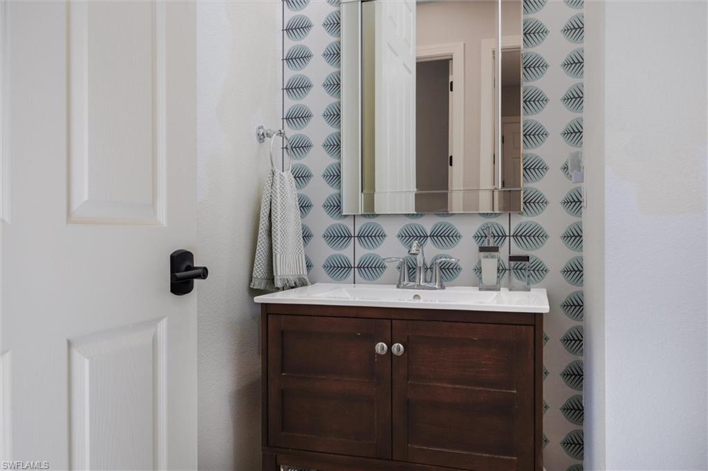 Bathroom vanity featuring a wood-finish cabinet, white countertop, and polished chrome faucet