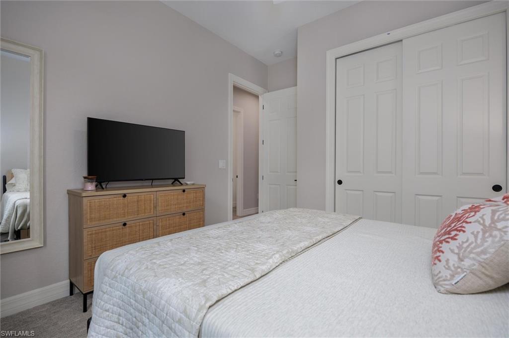 Bedroom featuring neutral wall paint, carpet flooring, and a large sliding closet with panel doors and black hardware