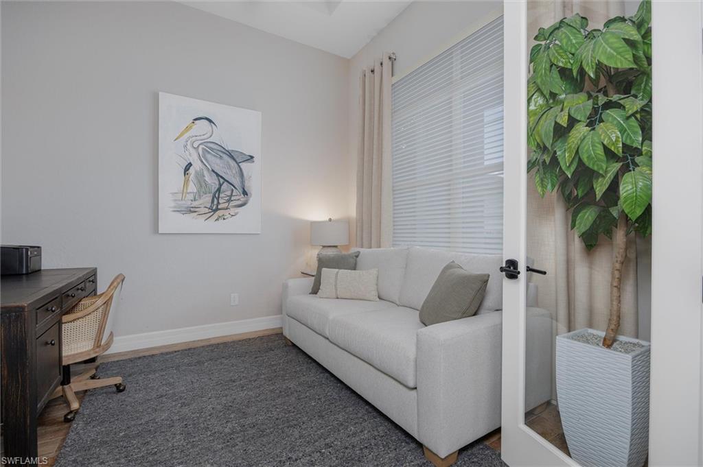 Versatile room featuring wood-finish flooring, a contemporary area rug, and a large window with blinds