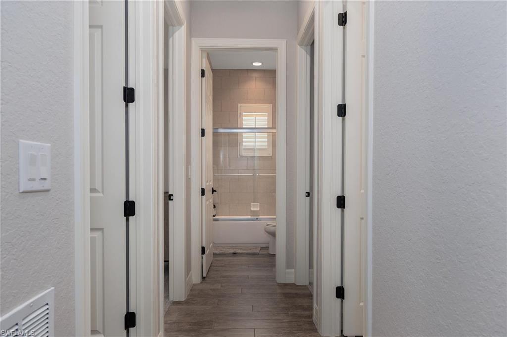 Hallway featuring wood-finish flooring, light grey painted walls, and white trim