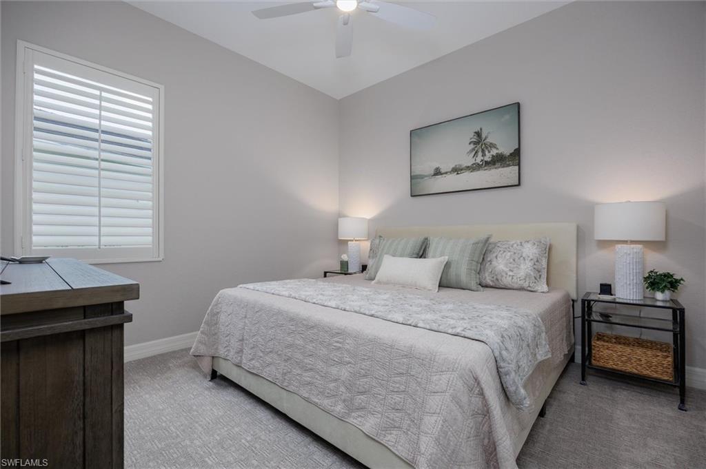 Bedroom featuring light gray walls, patterned carpeting, a ceiling fan, and window with plantation shutters