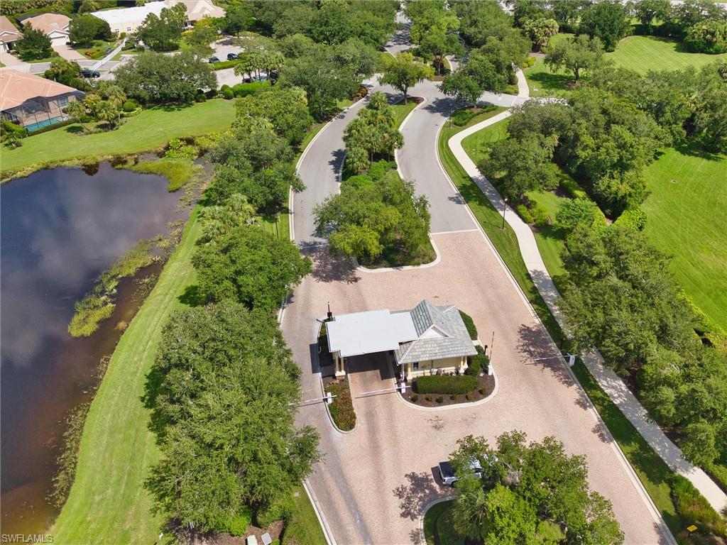 Gated community entrance featuring a guardhouse with a shingled roof and covered drive-through