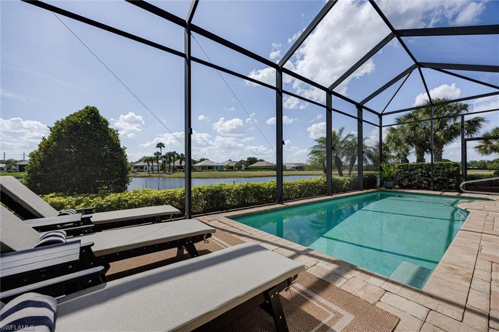 Screened pool enclosure featuring a rectangular pool with integrated steps, paver decking, and a surrounding privacy hedge