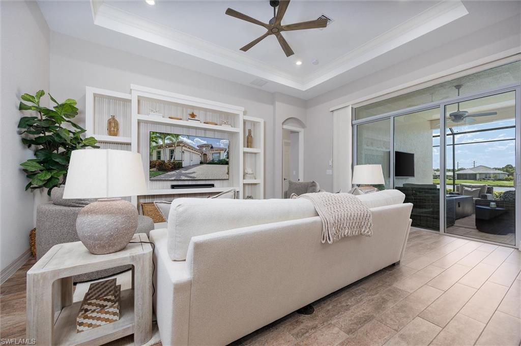 Living area featuring a tray ceiling, recessed lighting, and a ceiling fan