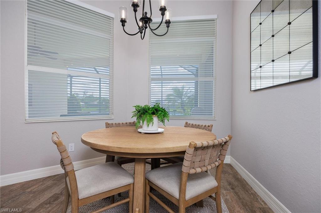 Bright dining area featuring two windows with horizontal blinds, a black metal chandelier, and wood-finish flooring